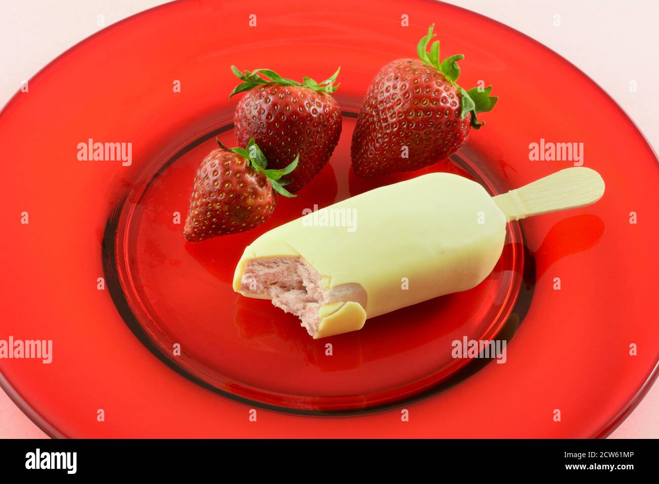 Erdbeer-Eiscreme in belgische weiße Schokolade getaucht mit Erdbeeren auf rotem Glasteller auf rosa Hintergrund Stockfoto