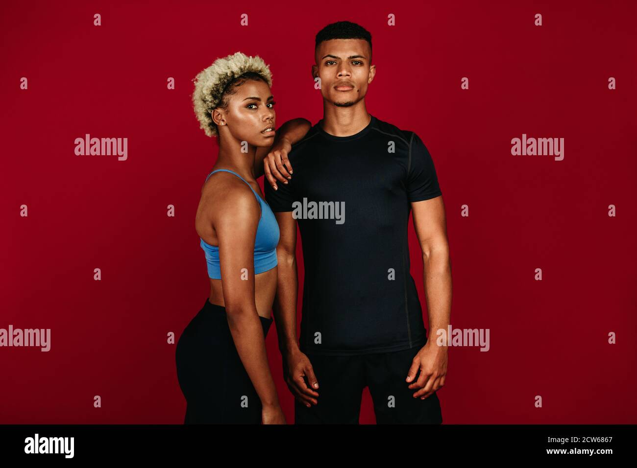 Muskulöses Fitness-Paar, das während des Trainings zusammen steht. afroamerikanische athletische Mann und Frau stehen zusammen auf kastanienbraunen Hintergrund. Stockfoto