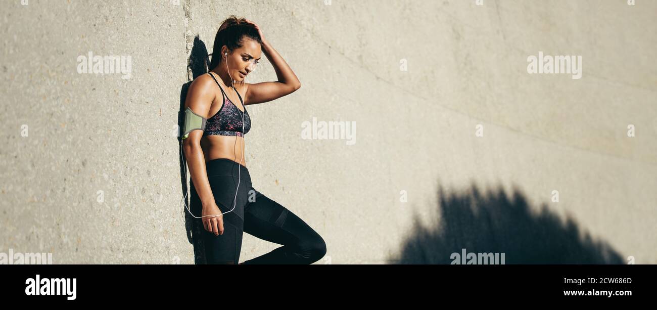 Sportliche Frau, die sich nach dem Laufen ausruhen kann. Panorama-Aufnahme von fit Frau Stockfoto