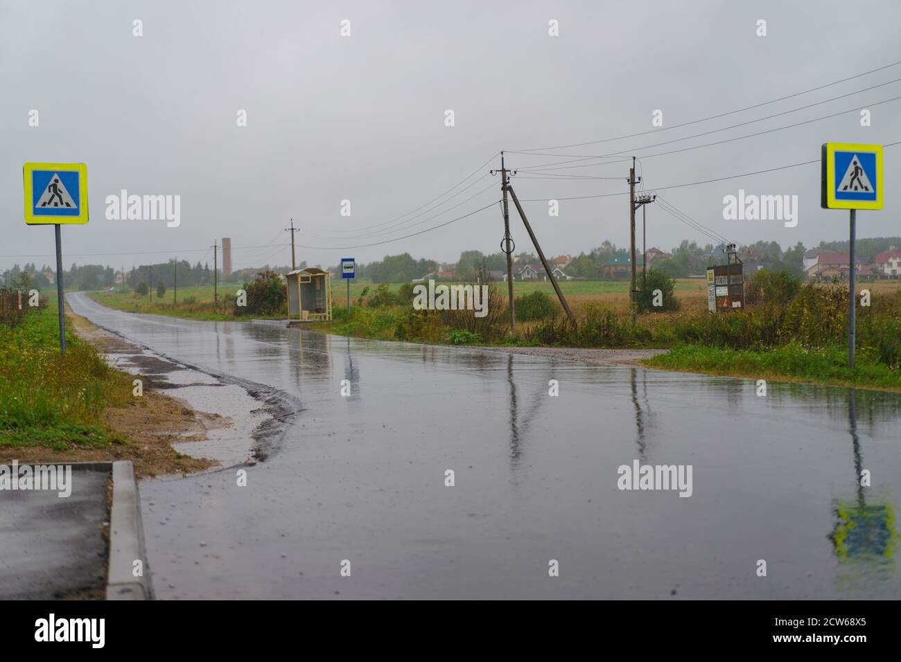 Der Herbst kommt in die russische Landschaft. Nasse Straße tagsüber. Kalte Dusche. Leere Bushaltestellen. Schilder der Fußgängerüberführung und öffentlichen Verkehrsmitteln Stockfoto