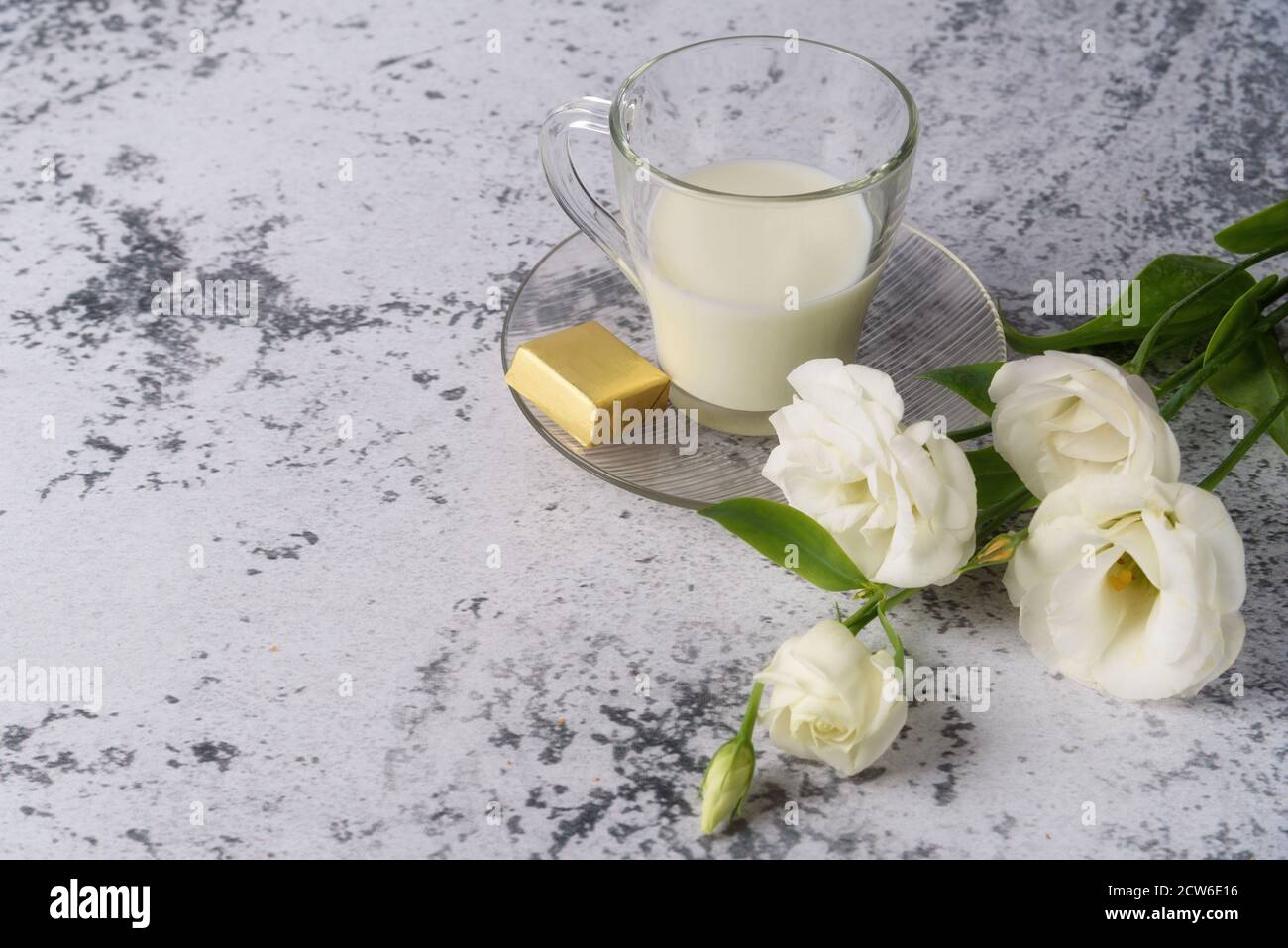Eine Tasse kalte, frische Milch zum Frühstück. Ein Bouquet von rosa, weiß, lila eustoma für Sie, auf einem grauen Betontisch. Stockfoto