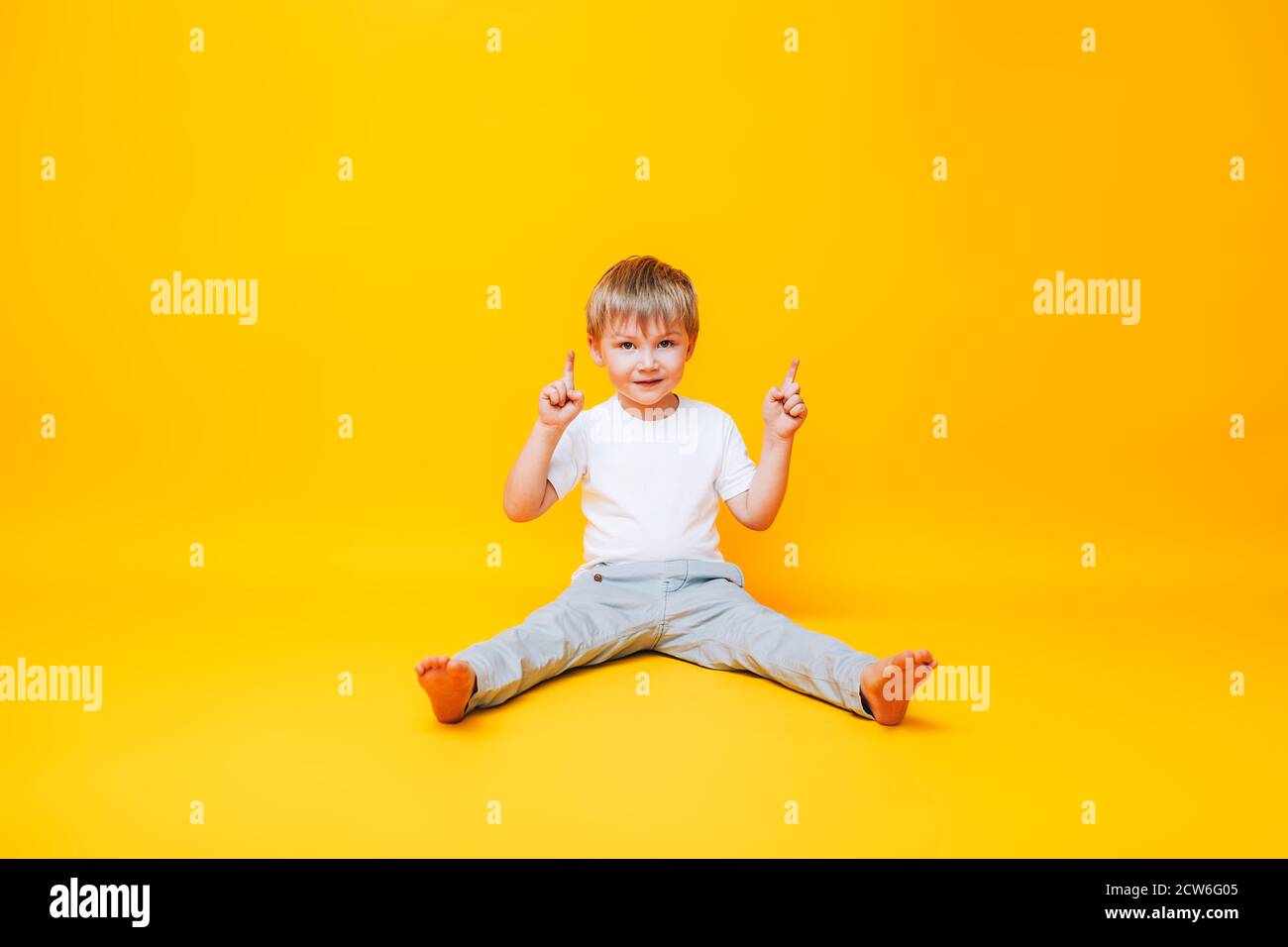 Netter Junge auf gelbem Hintergrund Punkte mit der Hand zur Seite, Foto für Werbeprodukt Stockfoto