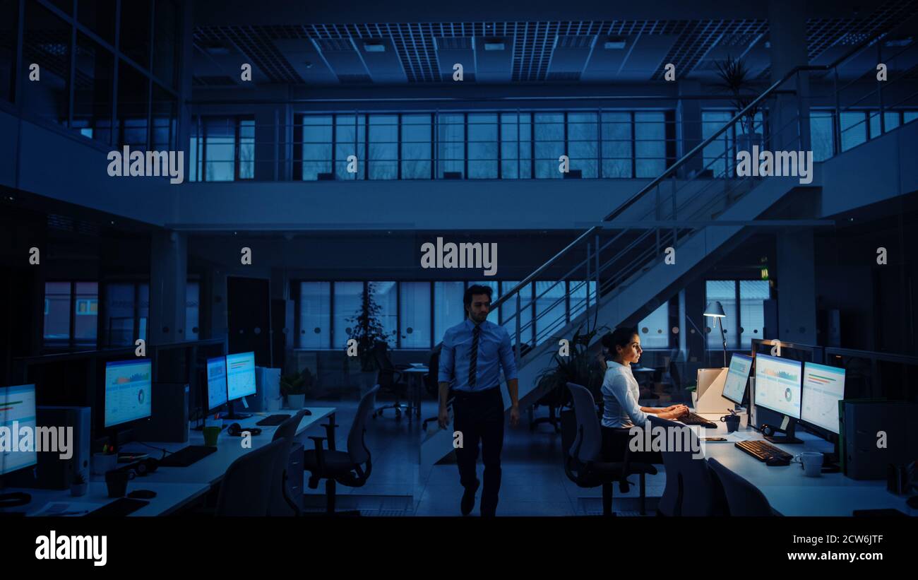 Arbeiten spät in der Nacht im Büro: Geschäftsfrau mit Desktop-Computer, Analysieren, mit Dokumenten, Probleme lösen, Projekt abschließen. Kollege Stockfoto