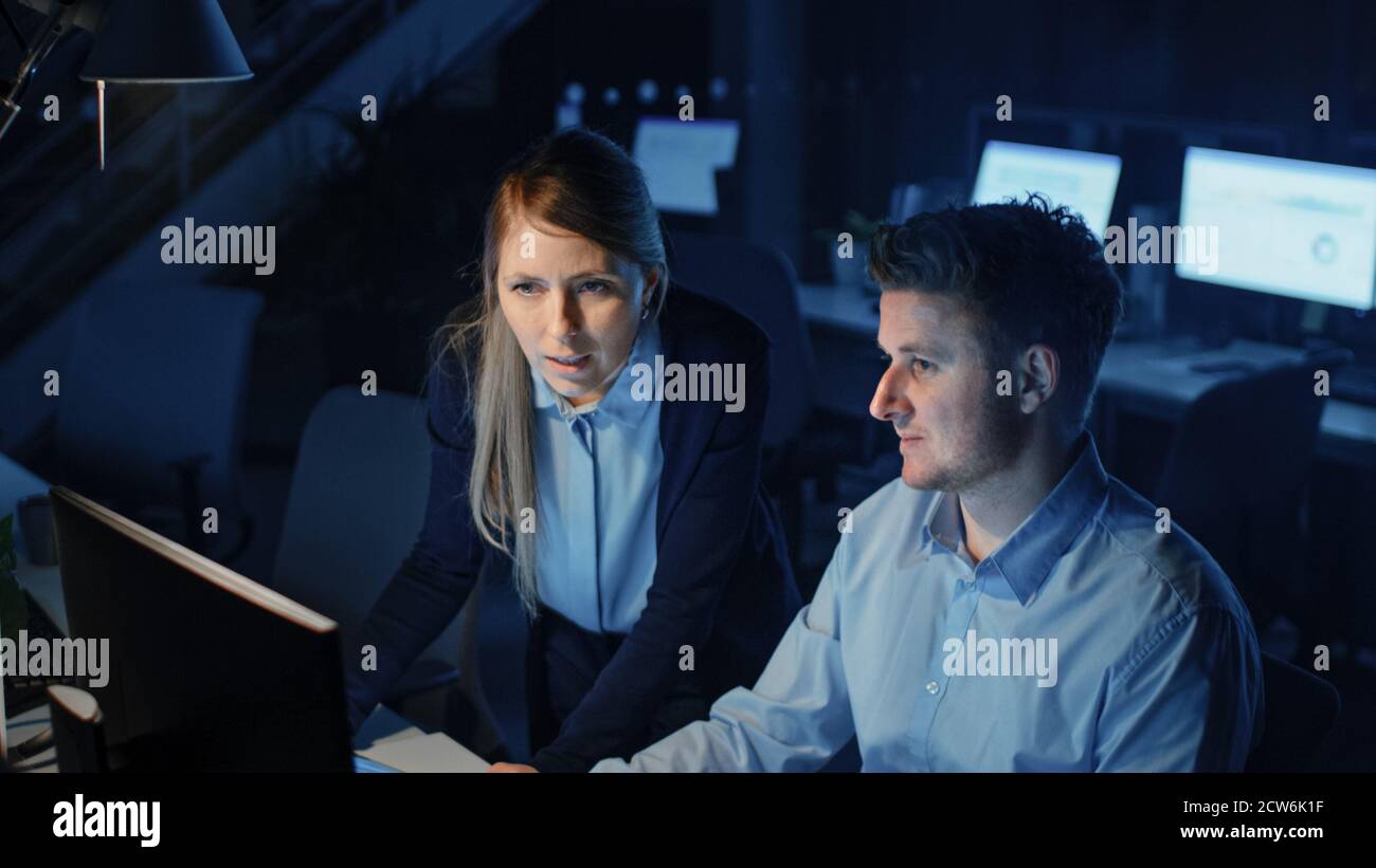 Ambitionierter und selbstbewusster Geschäftsmann nutzt Desktop-Computer, seine weibliche Projektmanagerin erklärt spezifische Aufgaben, Account-Handling, strategische Schritte Stockfoto