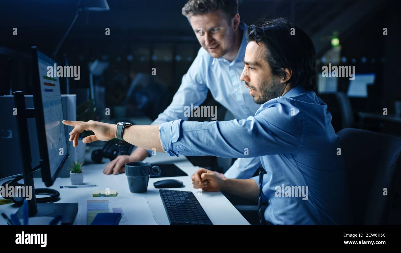 Ehrgeiziger und selbstbewusster Geschäftsmann nutzt Desktop-Computer, sein Projektmanager erklärt spezifische Aufgaben, Account-Handling und strategische Schritte Stockfoto