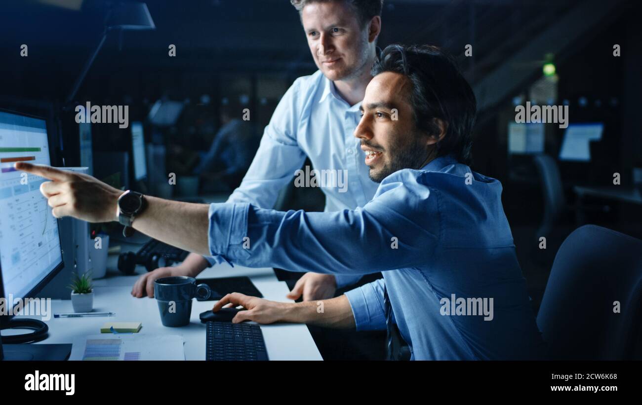 Ehrgeiziger und selbstbewusster Geschäftsmann nutzt Desktop-Computer, sein Projektmanager erklärt spezifische Aufgaben, Account-Handling und strategische Schritte Stockfoto