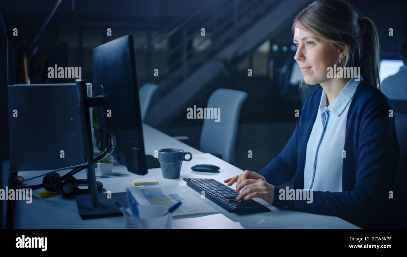 Arbeiten spät in der Nacht im Büro: Geschäftsfrau mit Desktop-Computer, Analysieren, mit Dokumenten, Probleme lösen, Projekt abschließen. Stockfoto