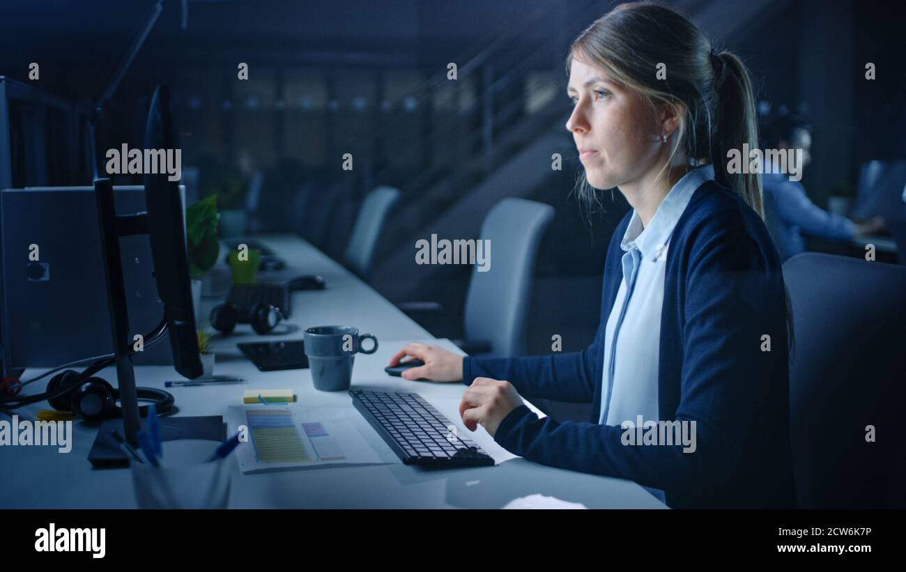 Arbeiten spät in der Nacht im Büro: Geschäftsfrau mit Desktop-Computer, Analysieren, mit Dokumenten, Probleme lösen, Projekt abschließen. Stockfoto