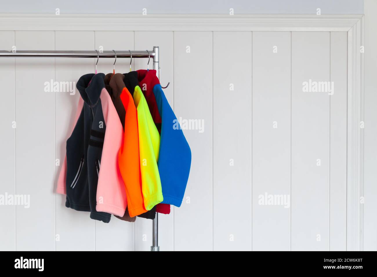 Bunte Fleecejacken hängen an Kleiderbügeln in der Nähe der weißen Wand In einem Geschäft Stockfoto Bunte Fleecejacken hängen an Kleiderbügeln in der Nähe der weißen Wand In einem Geschäft Stockfoto