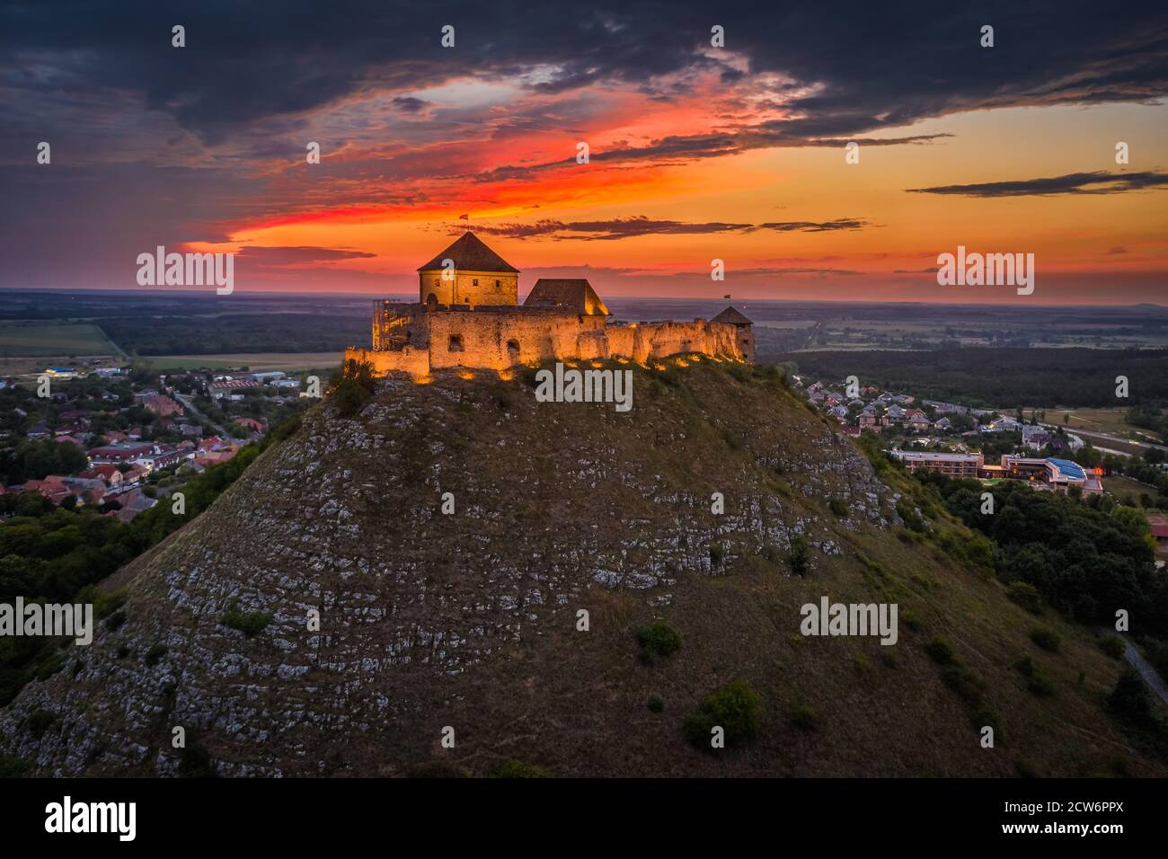 Sumeg, Ungarn - Luftaufnahme des berühmten beleuchteten Hohen Schlosses von Sumeg in Veszprem Grafschaft bei Sonnenuntergang mit bunten Wolken und dramatischen Farben der s Stockfoto