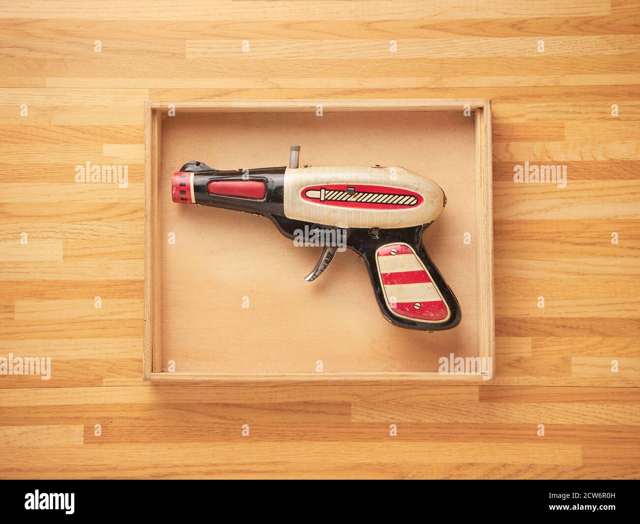 Zinn Spielzeugpistole in einer Holzkiste mit einem Holz Tabellenhintergrund Stockfoto