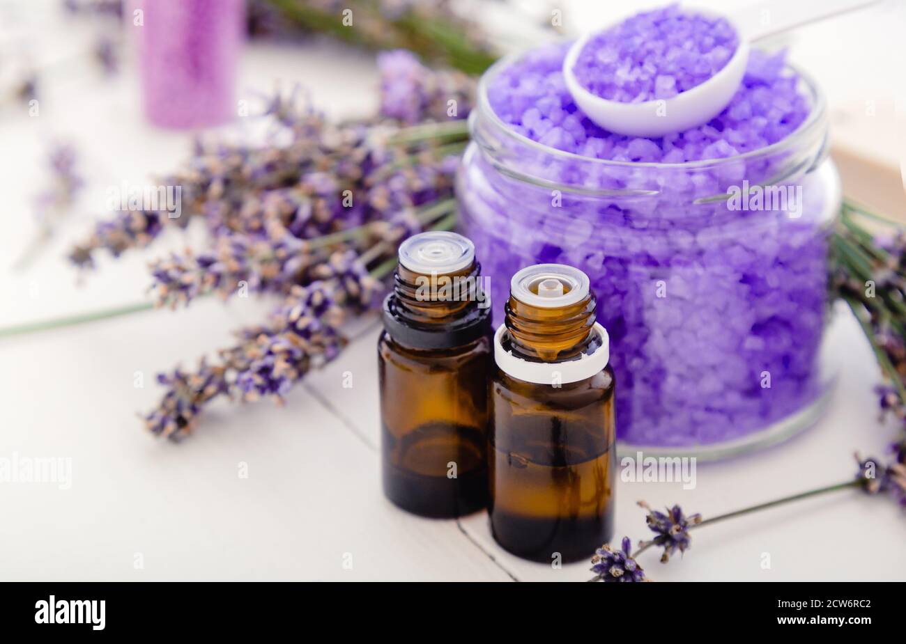 Lavendel ätherische Öle und violette Meersalz, Lavendelblüten. Lavendel Badeprodukte Aromatherapie Behandlung auf weißem Holzhintergrund. Hautpflege-Spa Stockfoto