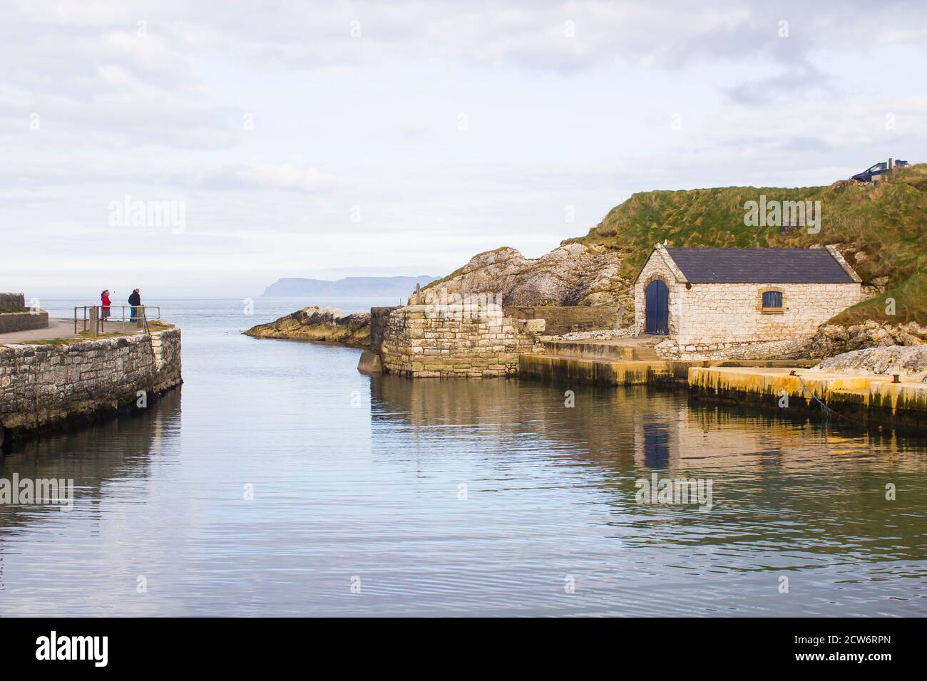 Der kleine Hafen von ballintoy an der Nord Küste von Antrim, Nordirland mit seinen alten Stein Bootshaus an einem Tag im Frühling Stockfoto