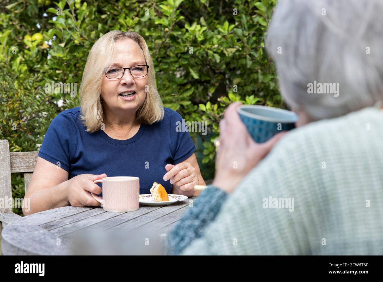 Ältere Frau Besucht Einsame Ältere Mutter Im Garten Während Der Sperre Stockfoto
