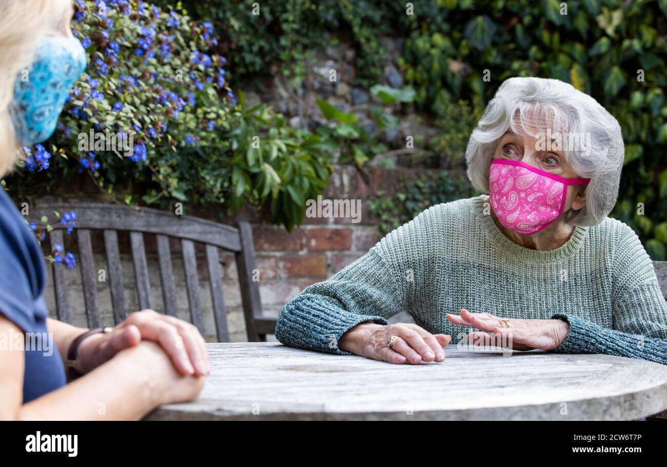 Reife Frau Trägt Maske Besuch Einsam Senior Mutter Im Garten Während Der Sperrung Stockfoto