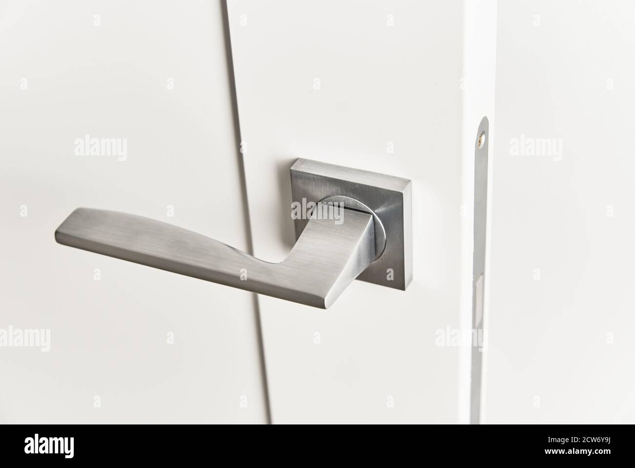 Silberner Türgriff an weißer Tür. Möbel Zubehör, Inneneinrichtung Stockfoto