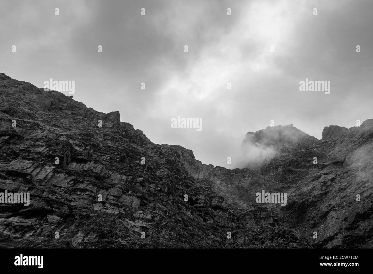 Schwarz-weißer Berggipfel unter dunklen Wolken Stockfoto