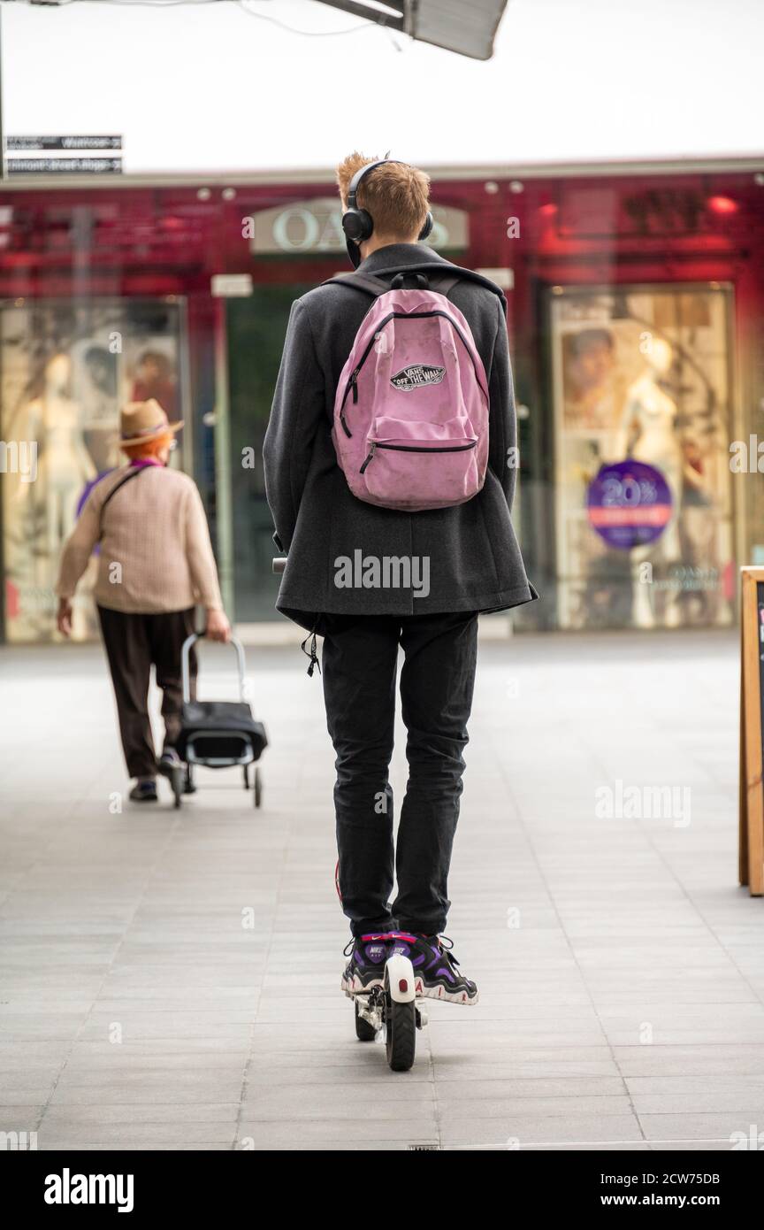 LONDON - 12. SEPTEMBER 2020: Mann mit pinkem Rucksack fährt Elektroroller durch ein Einkaufszentrum Stockfoto