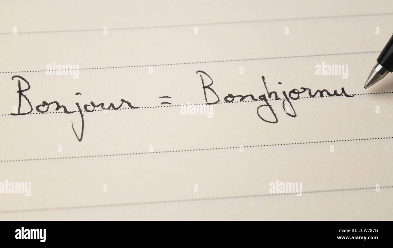 Anfänger korsische Sprache Lerner schreiben Hallo Wort Bonjour auf Französisch Und Bonghjornu auf Korsika für Hausaufgaben auf einem Notebook-Makro Aufnahme Stockfoto