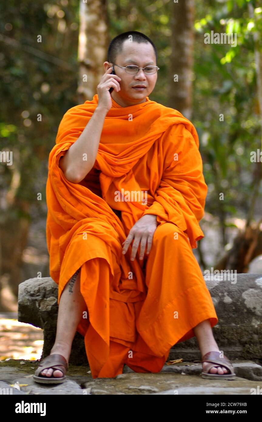 Ein buddhistischer Mönch in Safranroben, der ein Telefongespräch führt. Stockfoto