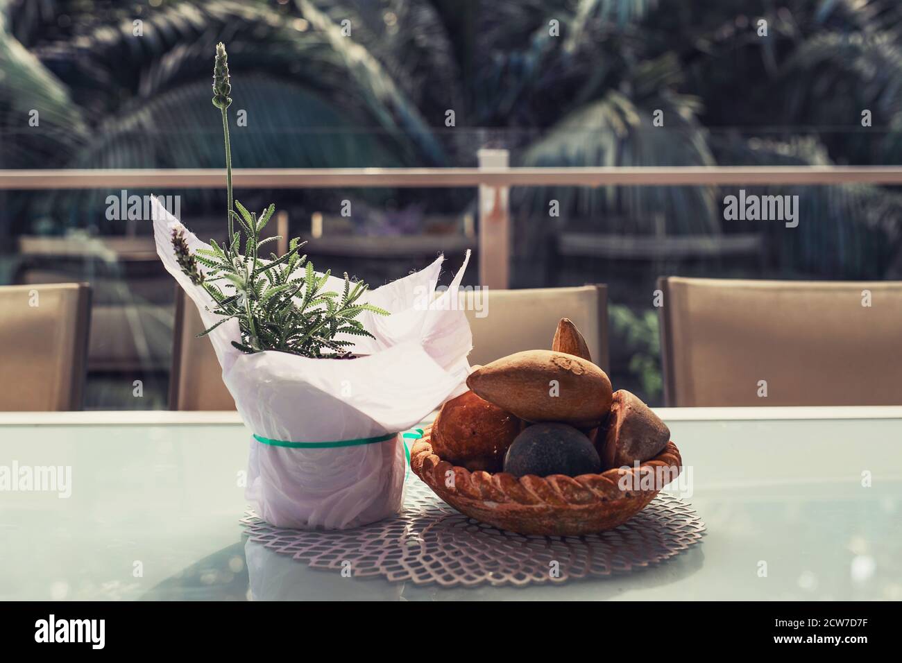 Lavendel in einem Topf mit einem weißen Papier und bedeckt Steinschüssel Dekorationen auf dem Tisch auf dem Balkon mit tropischen Regenwald im Hintergrund Stockfoto