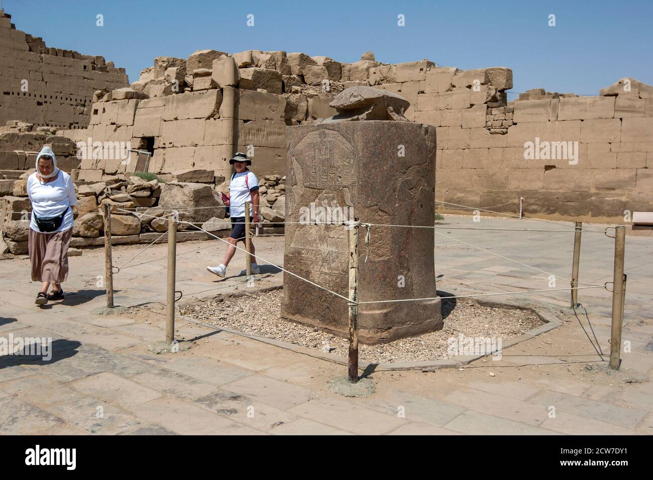 Touristen spazieren um die rote Granitstatue eines heiligen Skarabäus, der von Amenhotep III. Im Tempel von Karnak in Luxor in Ägypten gewidmet ist. Stockfoto