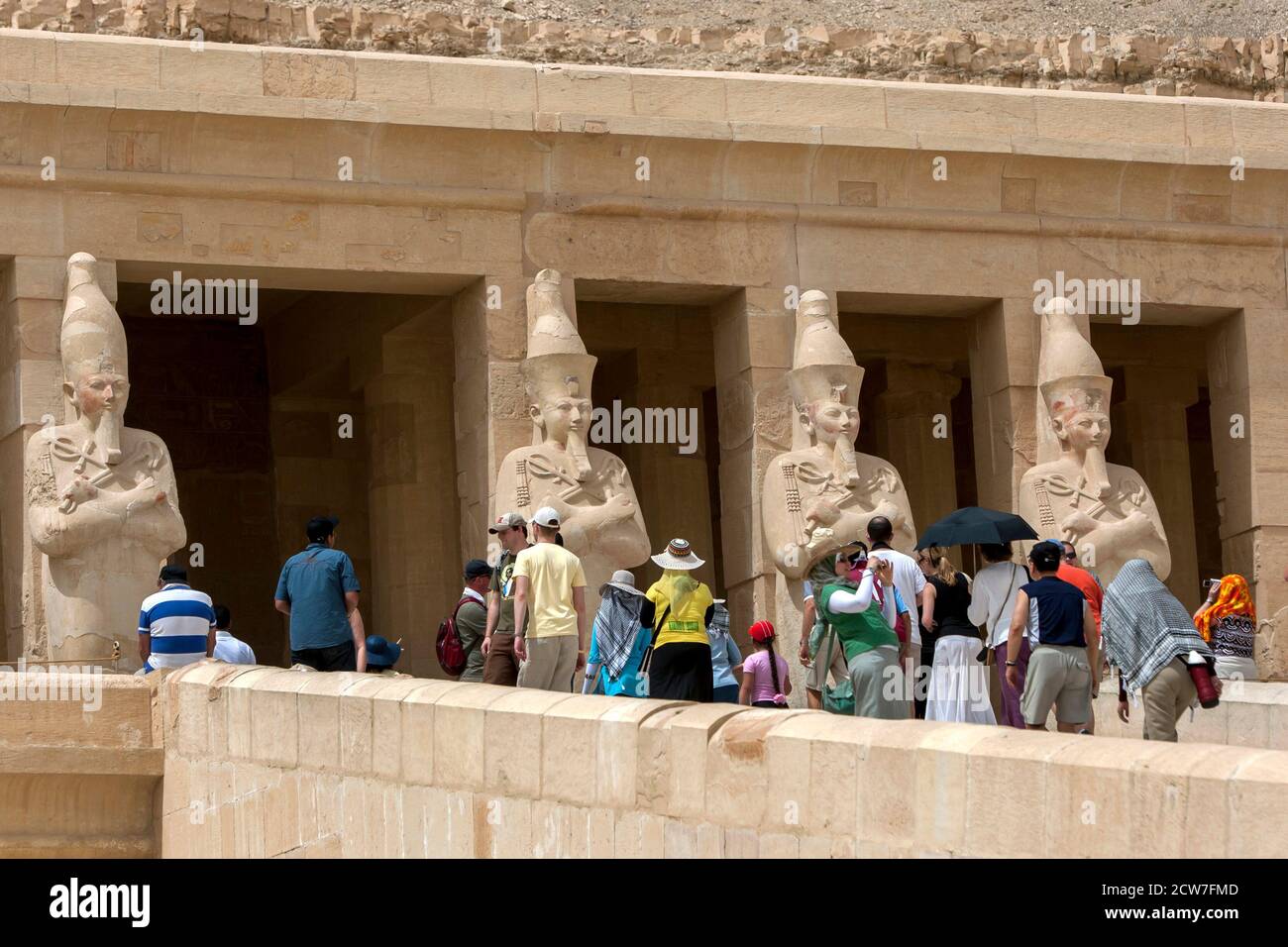 Touristen nähern sich den Osirid-Säulen auf der oberen Terrasse am Totentempel der Hatschepsut in Deir al-Bahri bei Luxor in Zentralägypten. Stockfoto