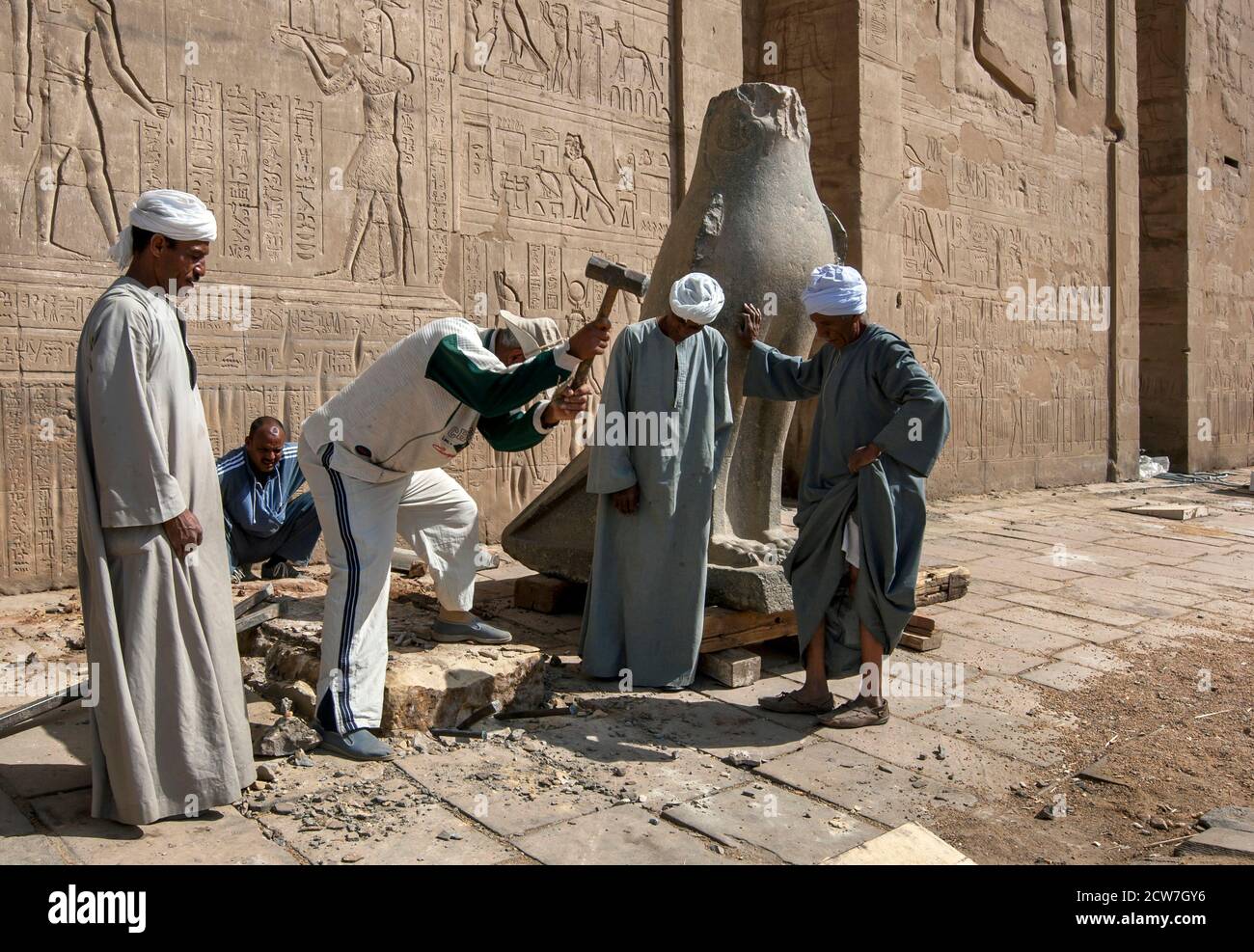 Arbeiter am Tempel des Horus bei Edfu in Ägypten, die eine neue Basis für einen der geschnitzten Steinfalken am Pyloneingang bilden. Stockfoto