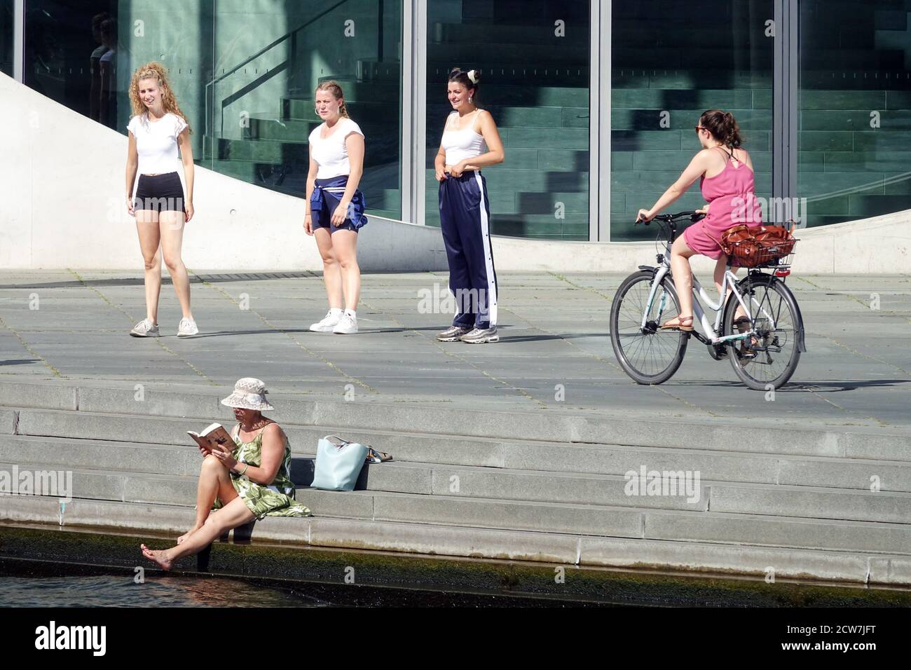 Fünf Frauen in Berlin Radfahren Eine Frau mit Hut liest ein Buch und eine andere fährt mit dem Fahrrad, das moderne Marie-Elisabeth-Lueders-Haus Berlin Lifestyle am Fluss Stockfoto