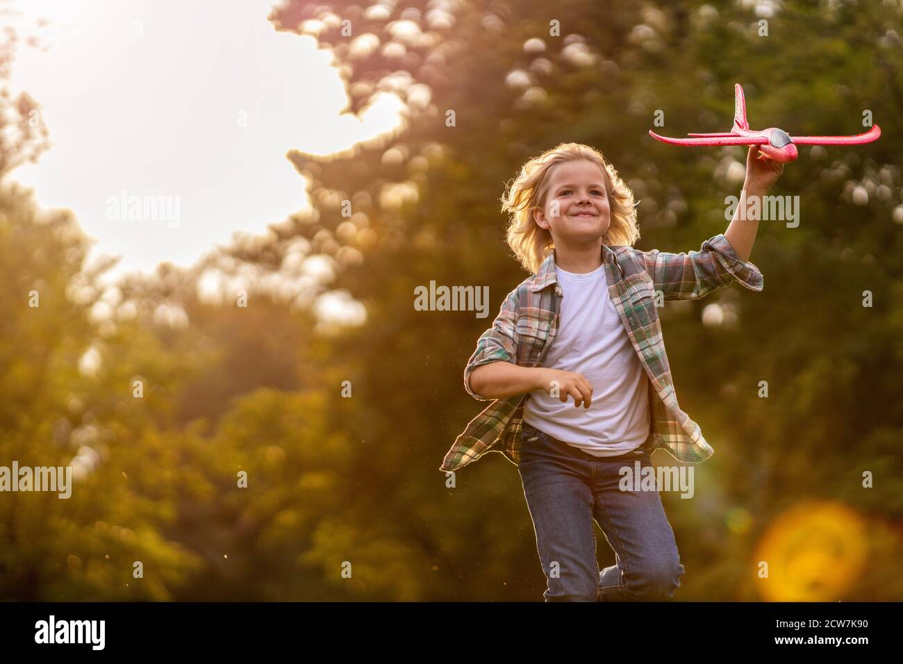 Kleiner Junge, der im Park mit dem Spielzeugflugzeug spielt Stockfoto