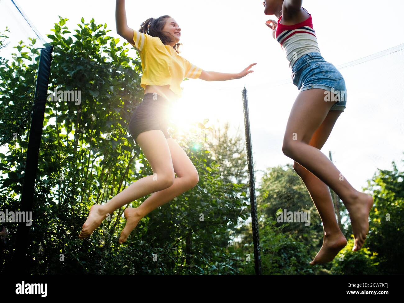 Low-Winkel-Ansicht der jungen Teenager Mädchen Freunde im Freien im Garten, springen auf Trampolin. Stockfoto