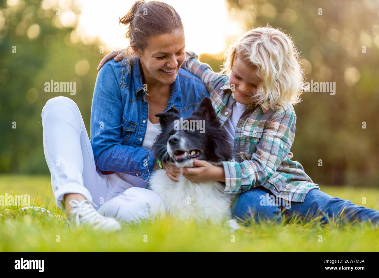 Glückliche Mutter und Sohn im Freien streicheln ihren Hund Stockfoto