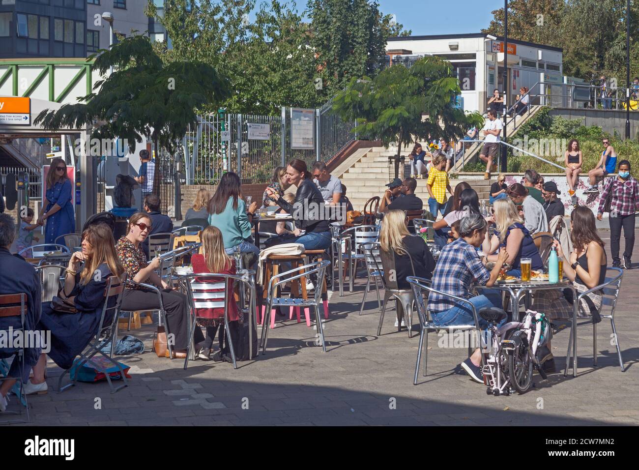 London, Borough of Lewisham. Kunden in einem Café am Eingang zum Bahnhof Brockley genießen die frühe Herbstsonne. Stockfoto