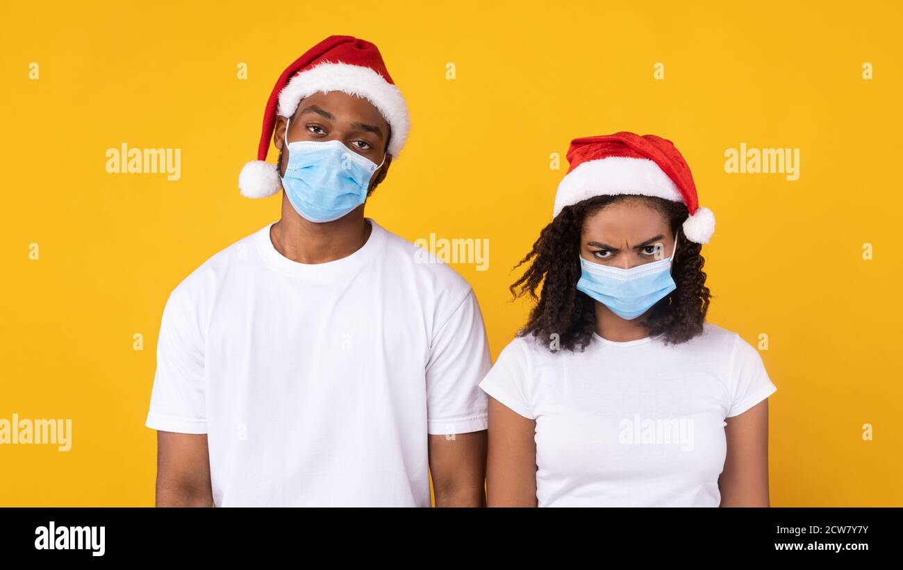 Afroamerikanisches Paar Feiert Weihnachten Mit Coronavirus Masken, Gelber Hintergrund Stockfoto