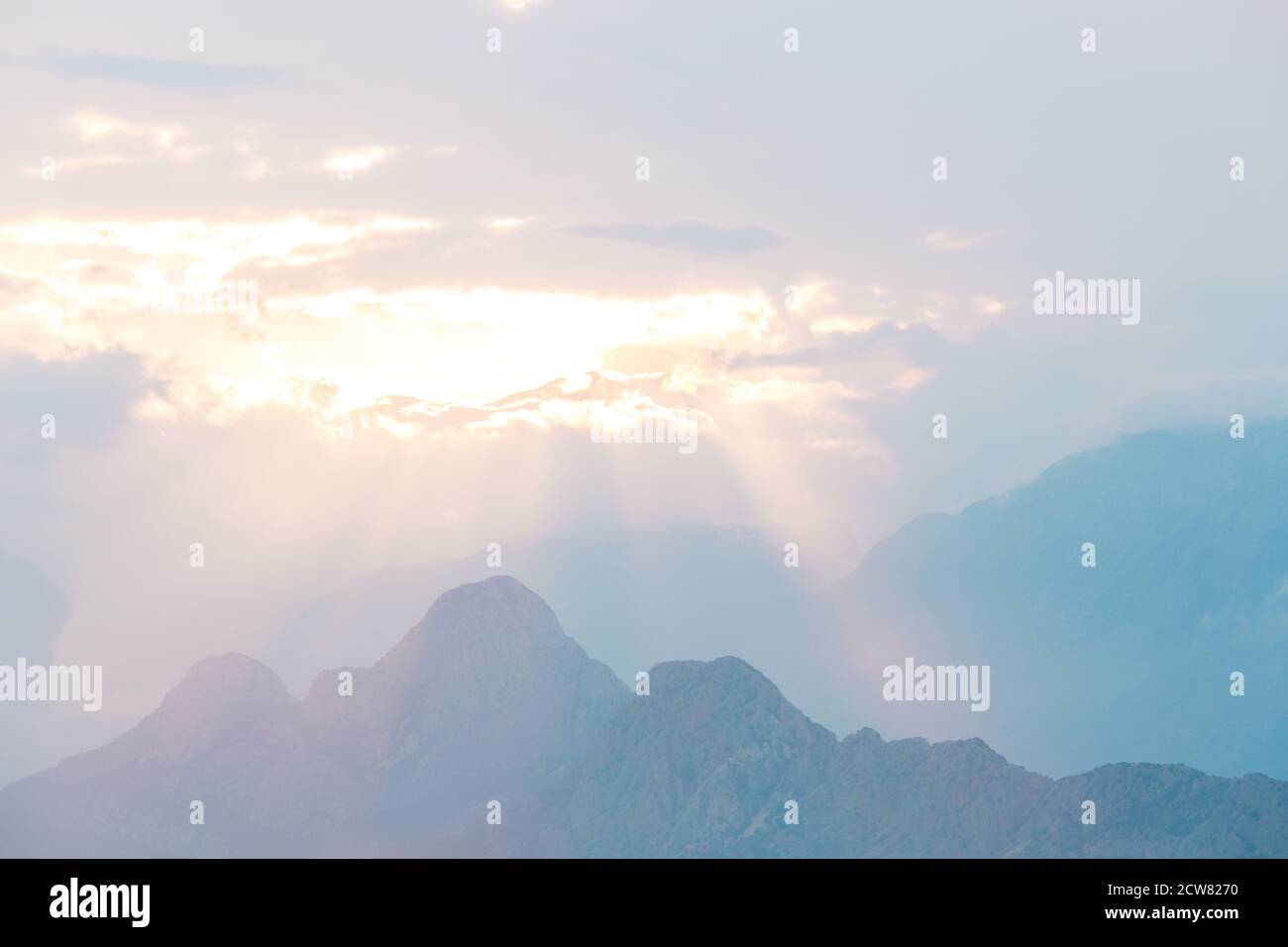 Sonnenuntergang in den Bergen, die Sonnenstrahlen durchbrechen die Wolken und erleuchten den Berg. Stockfoto