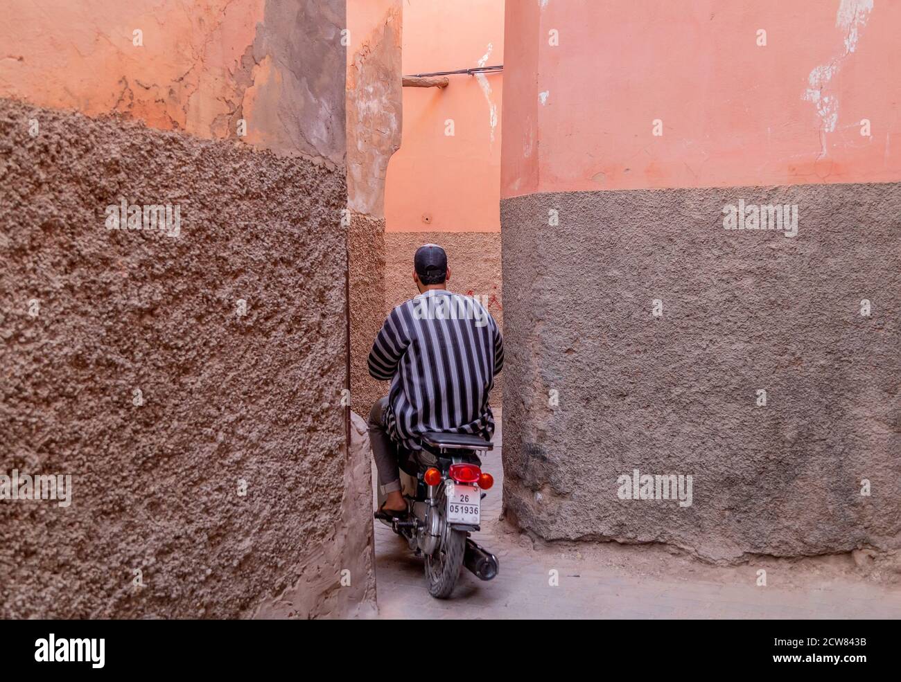 Motorradfahrer auf der schmalen Straße von Medina. Roller sind die typischen Verkehrsmittel in Marrakesch. Stockfoto