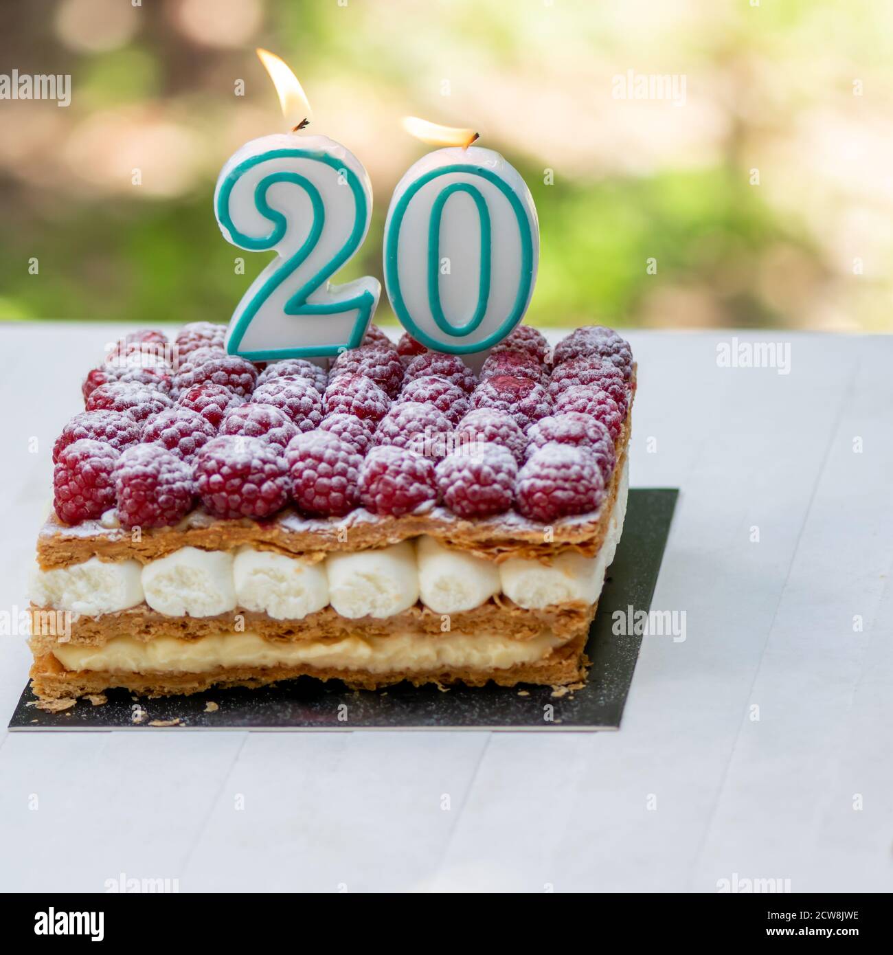 20. Geburtstag Himbeerkuchen mit brennenden Kerzen.Feier. Stockfoto