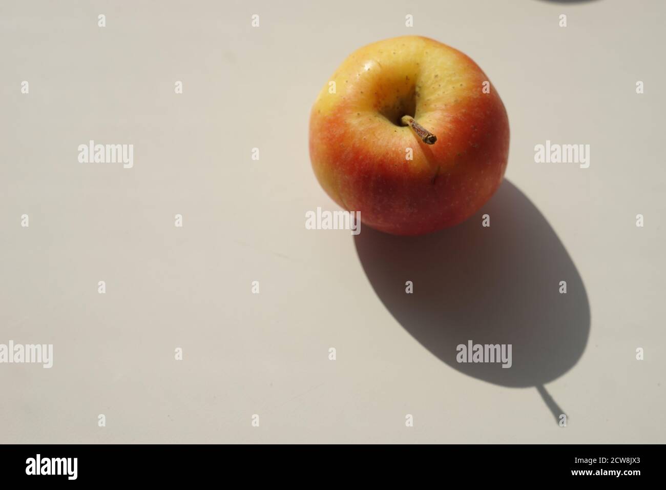 Gelb-orange Apfel auf einem weißen sonnigen Tisch. Stockfoto