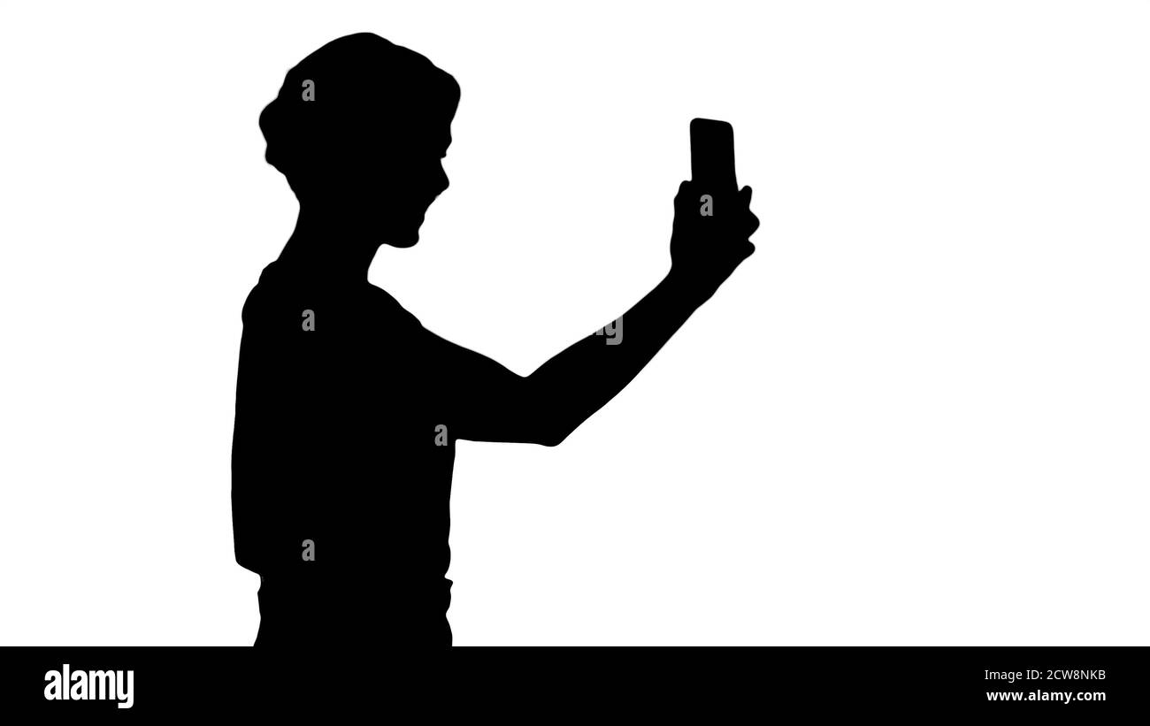 Silhouette schöne junge Frau zu Fuß und hält ein smartphon Stockfoto