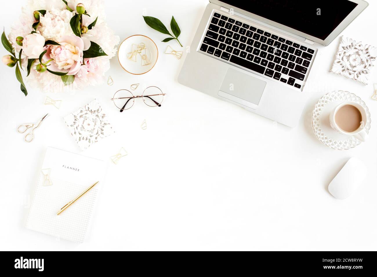 Flacher Schreibtisch für Damen. Weiblicher Arbeitsplatz mit Laptop, rosa Pfingstrosen Bouquet, Accessoires auf weißem Hintergrund. Draufsicht femininer Hintergrund. Stockfoto