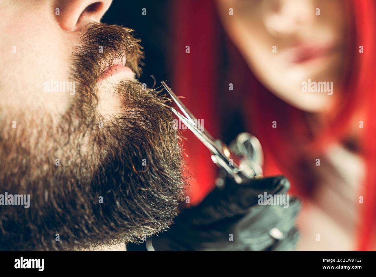 Besuch im Friseurladen. Der Meister macht einen Bartschnitt mit einer Schere Stockfoto