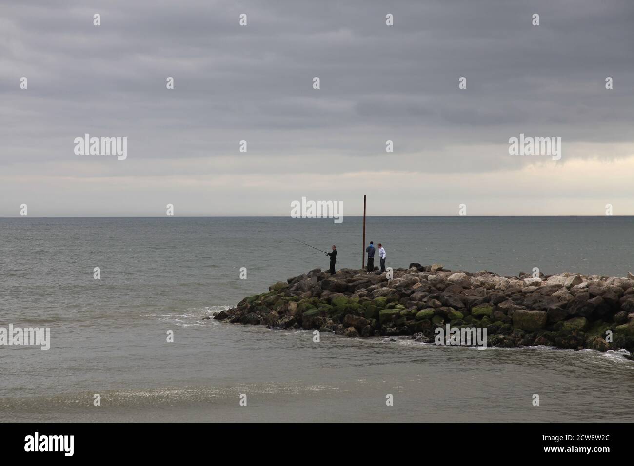 Fischer Seefischen am Ende einer Steingroyne, Dorset, England Stockfoto