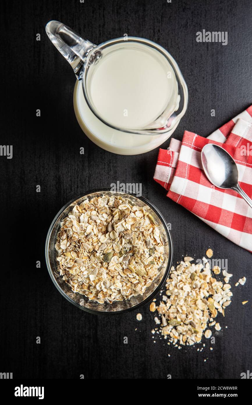 Müsli, Cerealien. Gesundes Frühstück mit Haferflocken und Milch auf schwarzem Tisch. Draufsicht. Stockfoto
