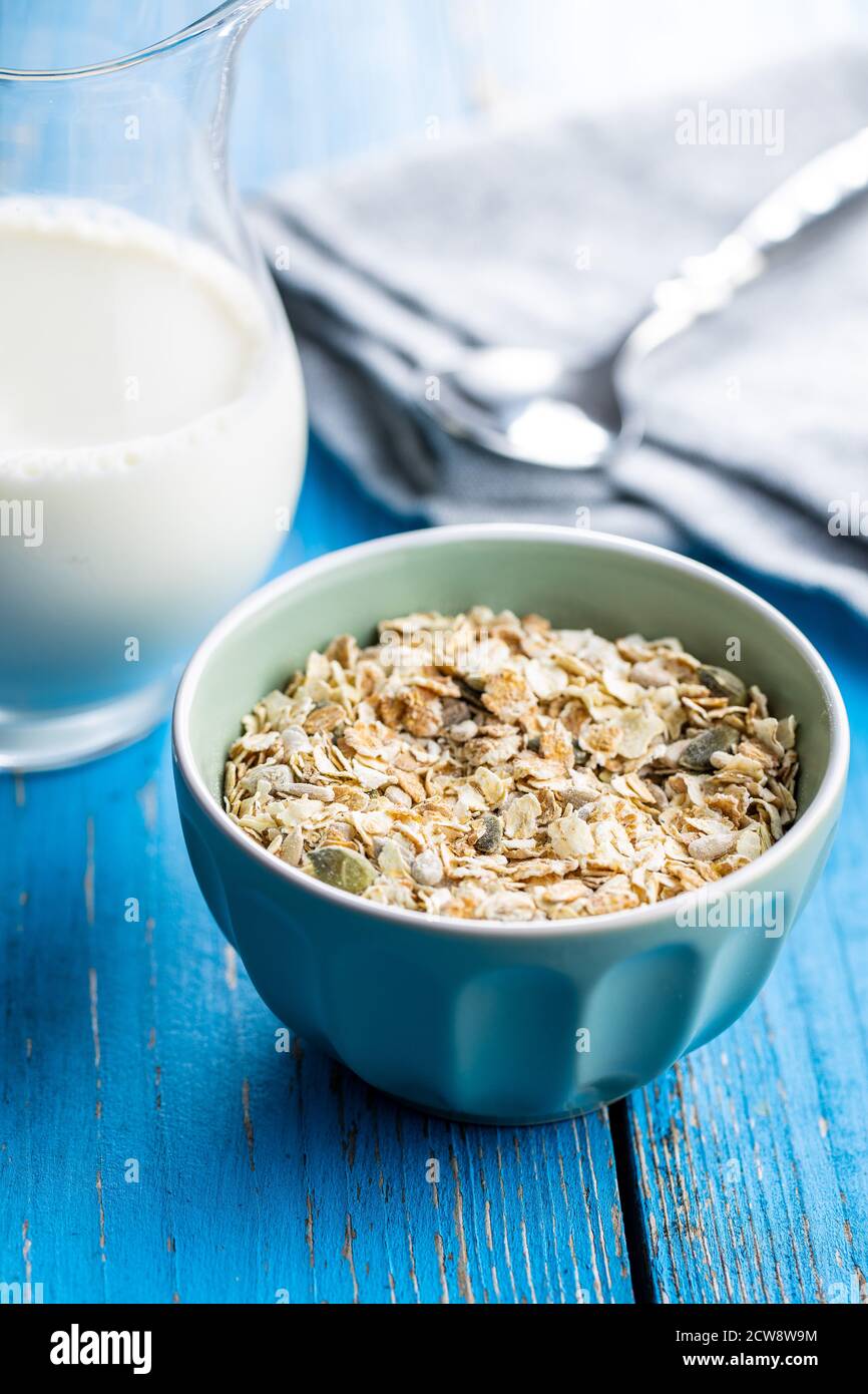 Müsli, Cerealien. Gesundes Frühstück mit Haferflocken in Schale auf blauem Holztisch. Stockfoto