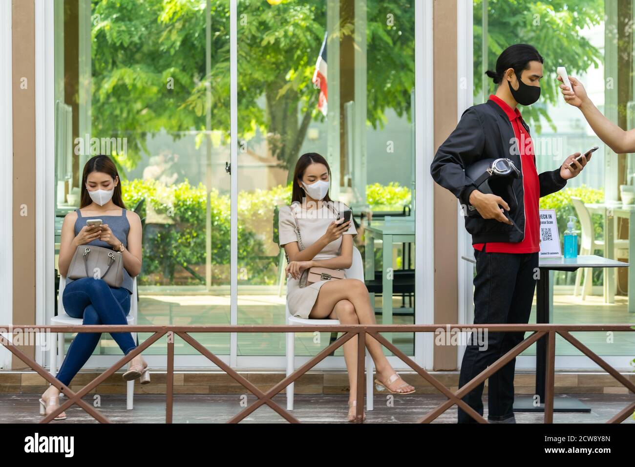 Nehmen Sie die Temperatur für den Kunden mit Gesichtsmaske vor dem Eintreffen in Restaurant mit sozialen Abstand Warteschlange in der Linie New Normal nach Coronavirus covid-19 Pan Stockfoto