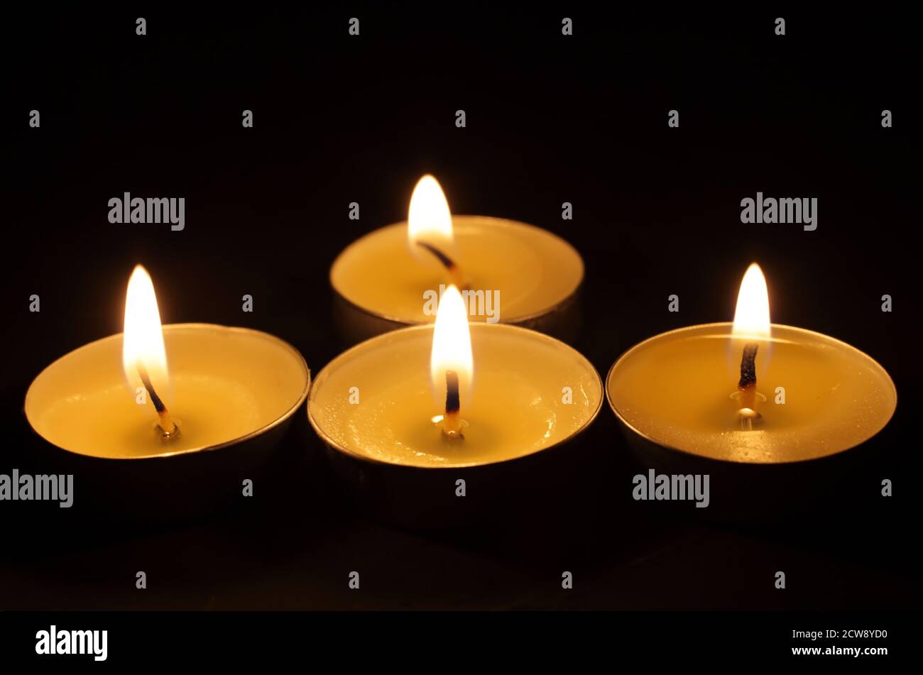 Vier brennende Kerzen. Weihnachtskerzen brennen im Dunkeln. Fokus ist im Vordergrund, Kerzen sind nicht fokussiert. Stockfoto