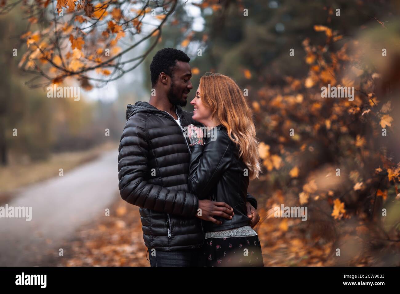 Glücklich niedlich interracial paar posiert in verschwommenen Herbst Park Hintergrund, schwarzer Mann und weiß rothaarige Frau Stockfoto