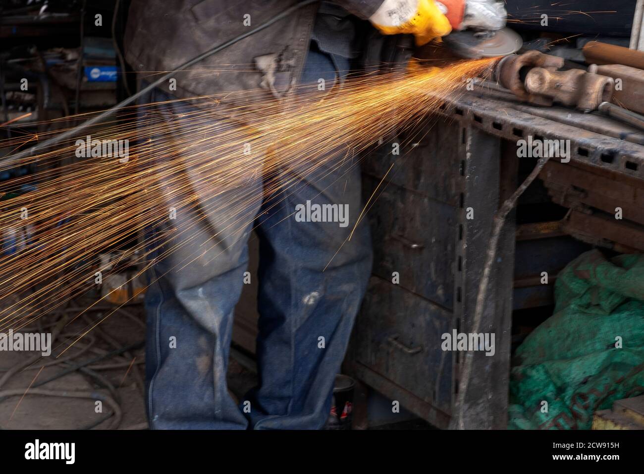 Schweißer verwendet Schleifstein auf Stahl in der Herstellung mit Funken Stockfoto