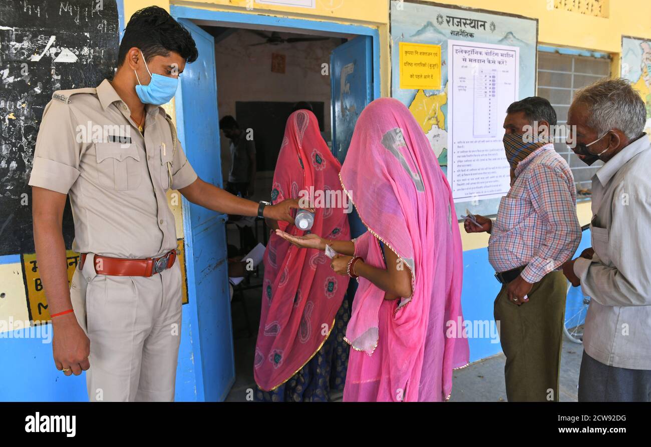 Beawar, Rajasthan, Indien, 28. September 2020: Die Wähler bekommen ihre Hände desinfiziert, während sie warten, um ihre Stimmen für Panchayati Raj Wahlen abzugeben, inmitten der laufenden Coronavirus-Pandemie, in Jhala KI Chauki Dorf in der Nähe von Beawar. Über 83.50 Prozent der 31.95-lakh Wähler ihre Stimmen in der ersten Phase der 947 Gramm Panchayat (Dorfrat) Wahlen in 25 Bezirken im ganzen Staat. Die Richtlinien im Zusammenhang mit COVID-19 wurden bei der Wahl nicht befolgt. Die Wähler tragen Gesichtsmasken, haben aber keine soziale Distanzierung beibehalten. Kredit: Sumit Saraswat/Alamy Live Nachrichten Stockfoto