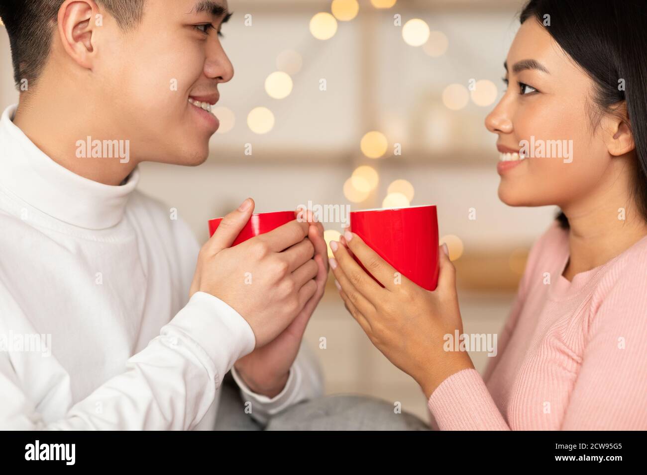 Liebevolle Asiatische Paar Trinken Kaffee Holding Tassen Sitzen Zu Hause Stockfoto